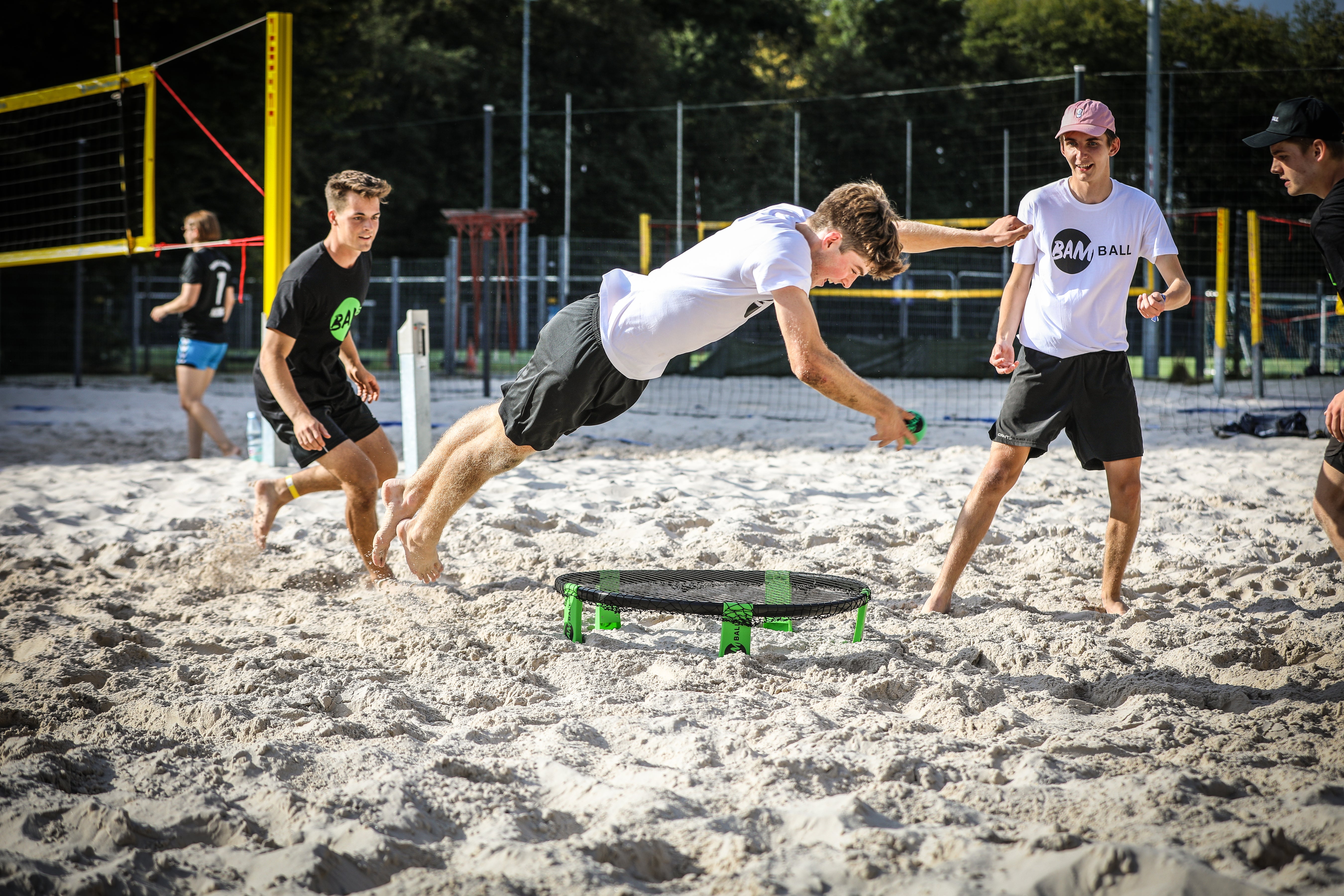 Roundnet Spiel am Strand, Spieler im Sprung, um den Ball aufs Netz zu schlagen