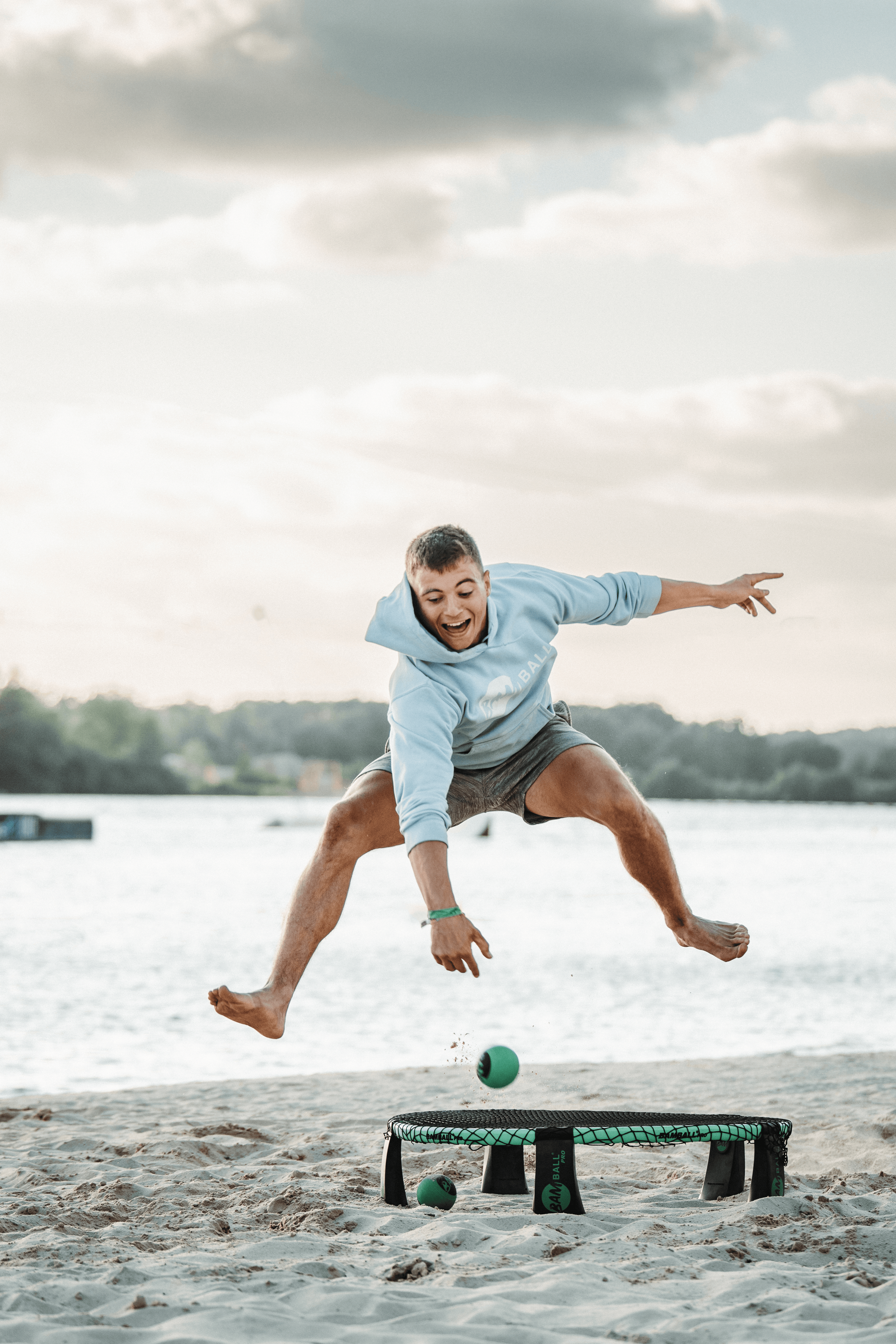 Ein ROundnet Spieler am Strand, wie er den Ball durch die Beide aufs Netz spielt