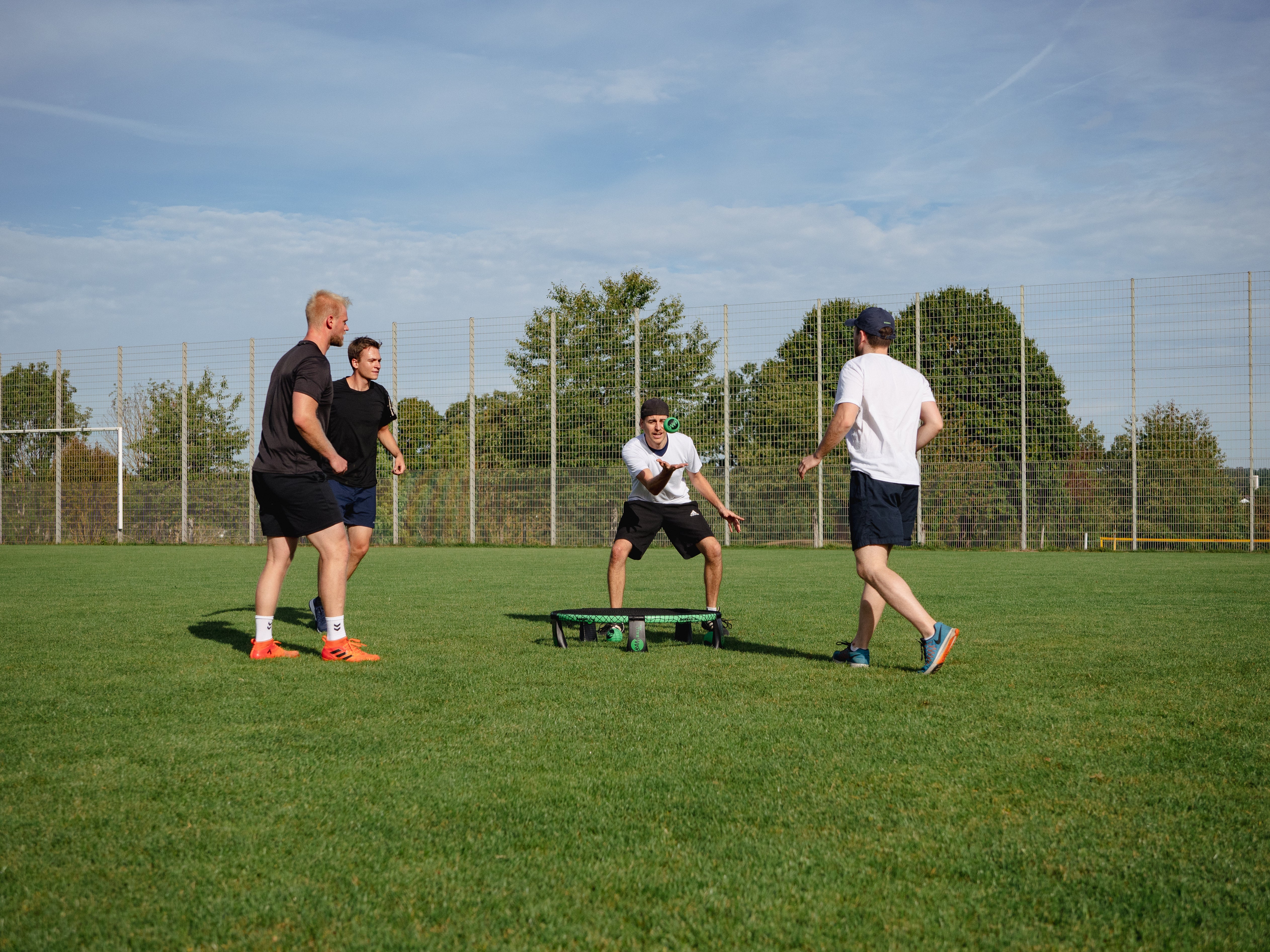 Vier Spieler, die Roundnet auf einem Rasen spielen