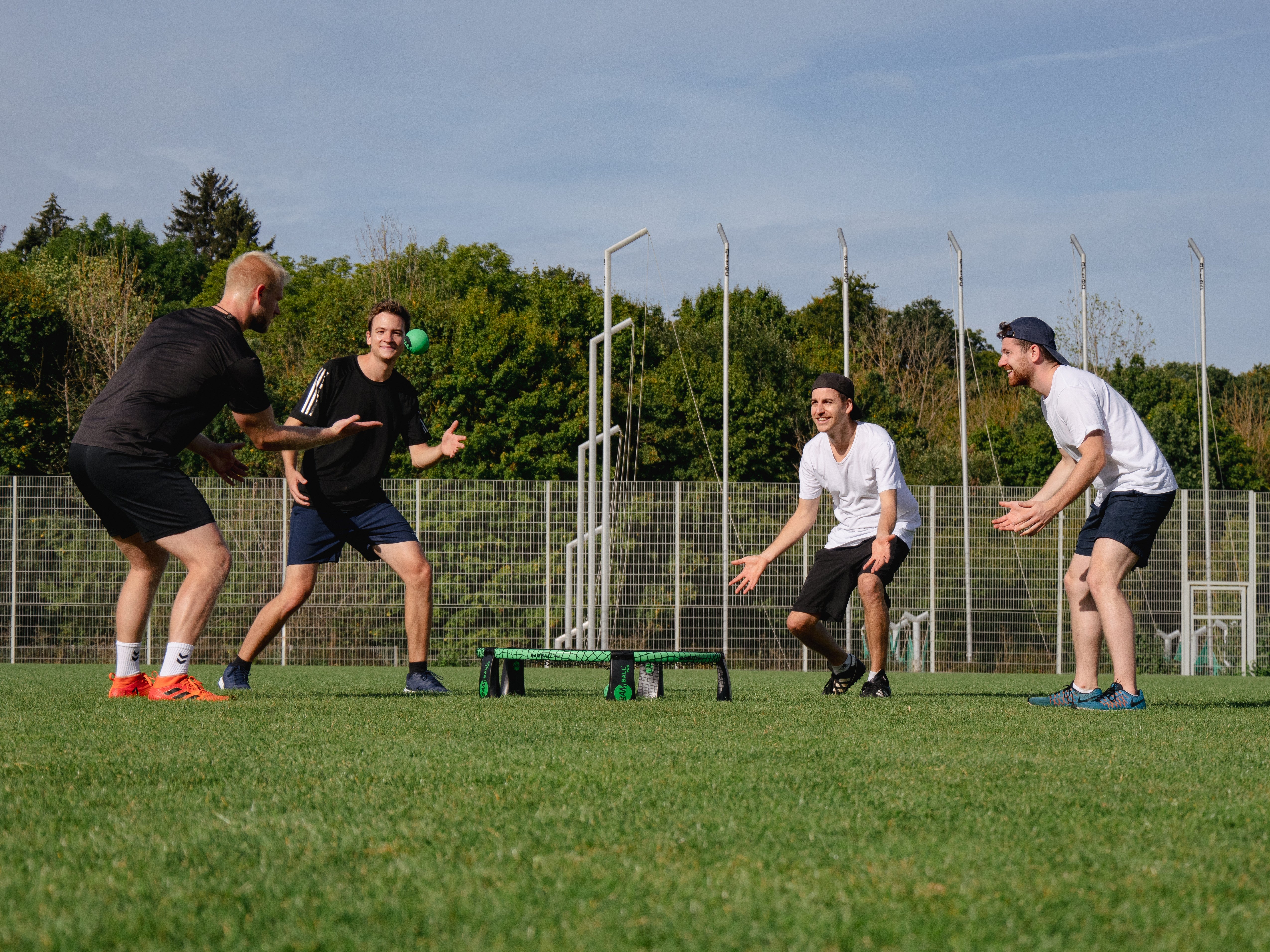 vier Roundnet Spieler beim Sport, während einer den Ball stellt