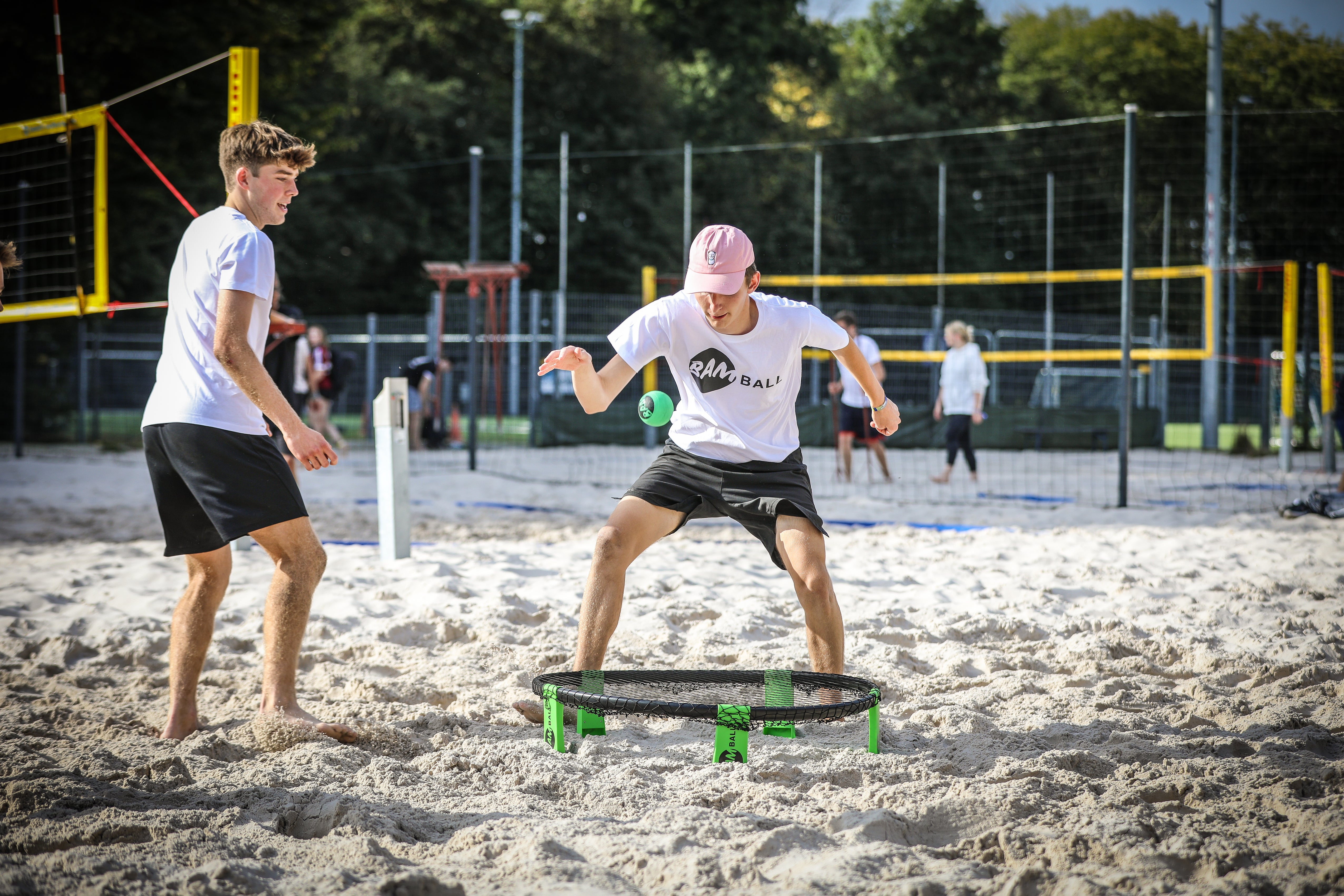 Zwei Roundnet Sportler im Sand, ein Spieler ist dabei, den Ball aufs Netz zu schlagen