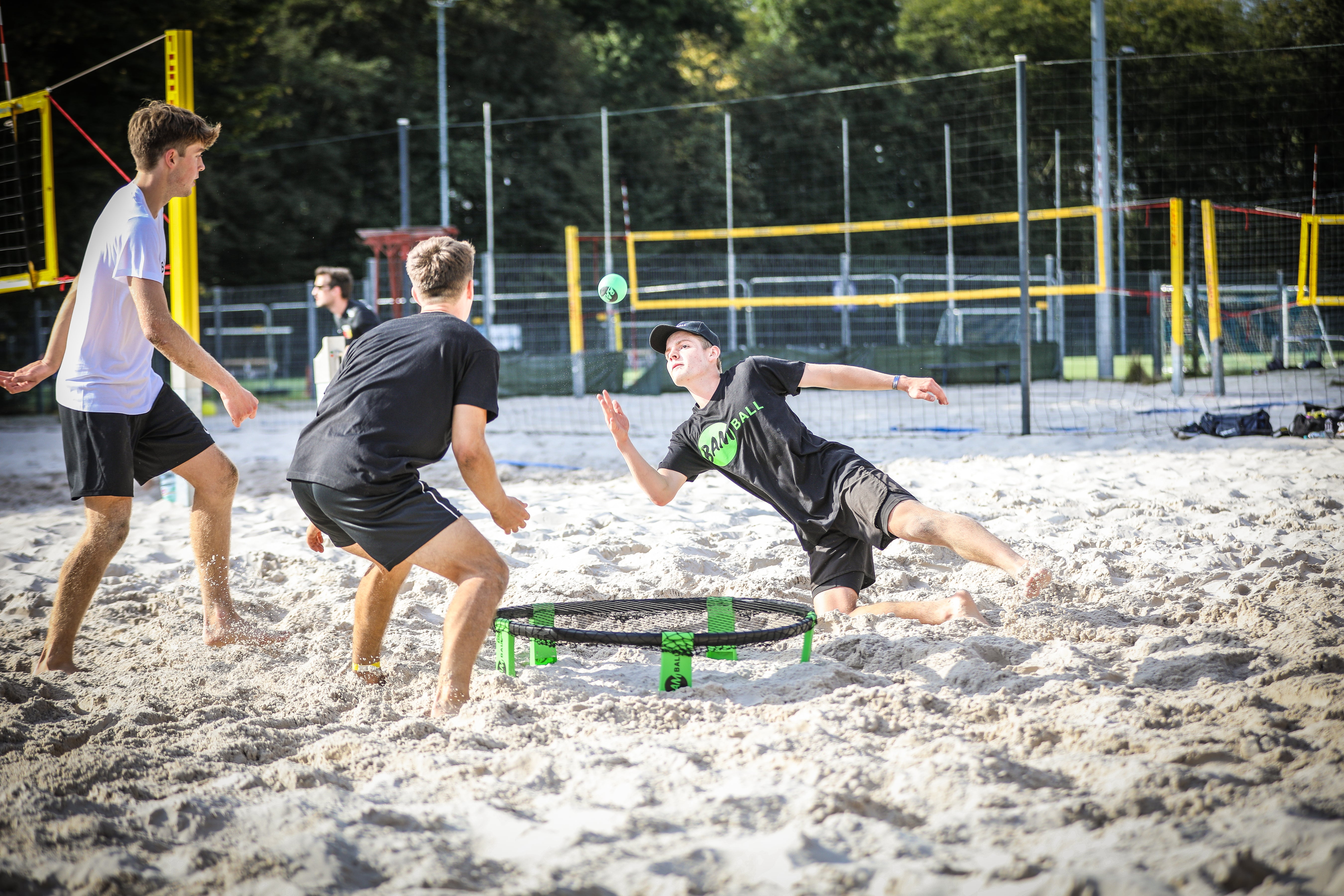 Ein Roundnet Spieler im Sand, der sich für den Ballkontakt auf den Boden wirft